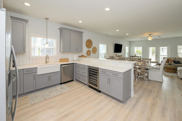 A modern kitchen with grey cabinets, a white countertop, and a built-in dishwasher.