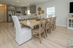 A modern kitchen with grey cabinets, stainless steel appliances, and a dining area with a wooden table and chairs.