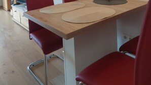 Ein Essbereich mit einem Holztisch, roten Stühlen und einer Wandleuchte.