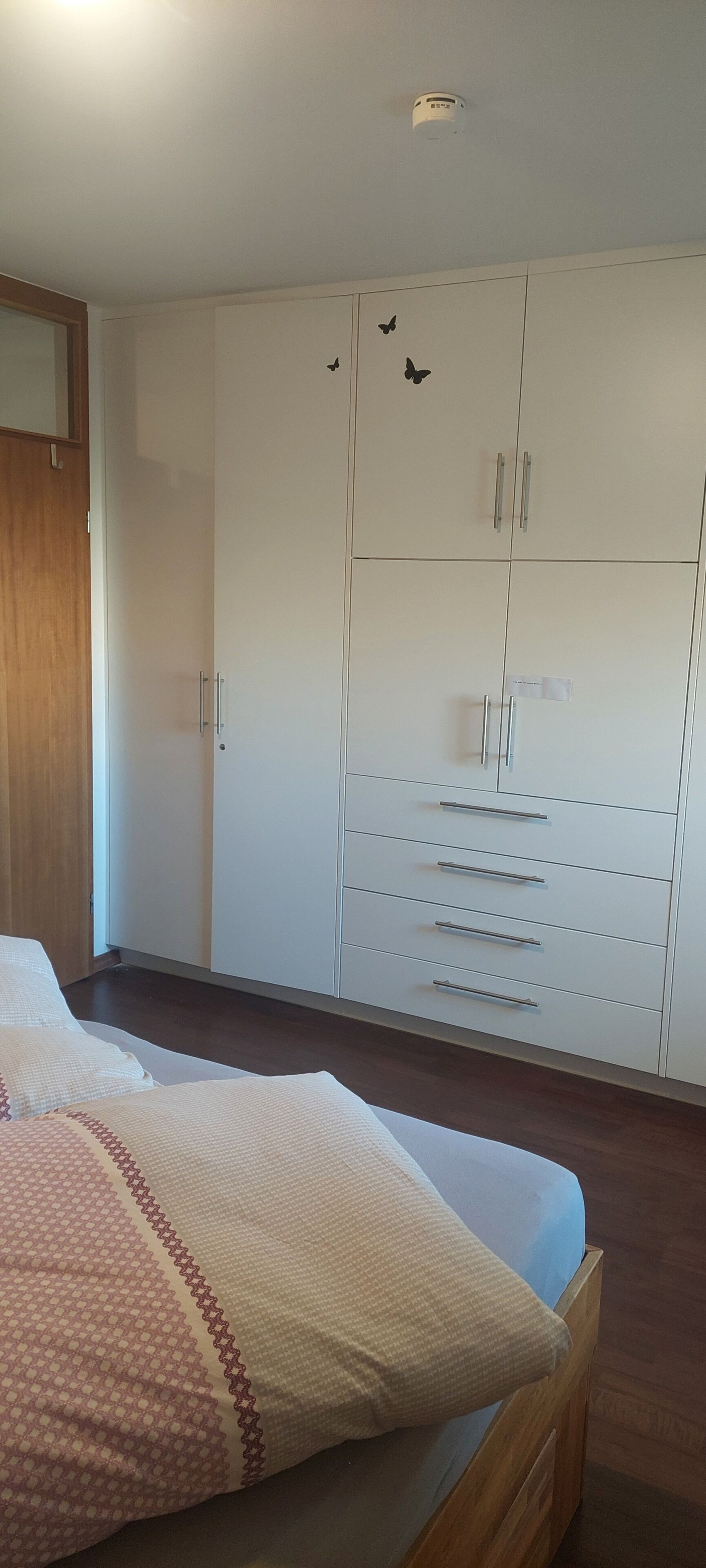 A bedroom with a bed, a wardrobe, and a ceiling light.