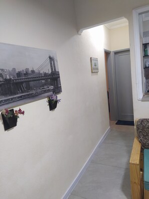 A hallway with a cityscape mural, a door, and a small plant. - Vila Tupy, a 100 m da Praia (Vila Assuncao Praia Grande)