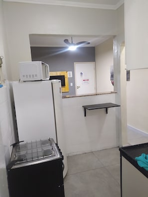 A kitchen with a microwave, refrigerator, stove, and a ceiling fan. - Vila Tupy, a 100 m da Praia (Vila Assuncao Praia Grande)