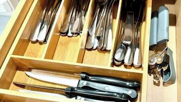 A drawer with various kitchen utensils including spoons, forks, knives, and a whisk.