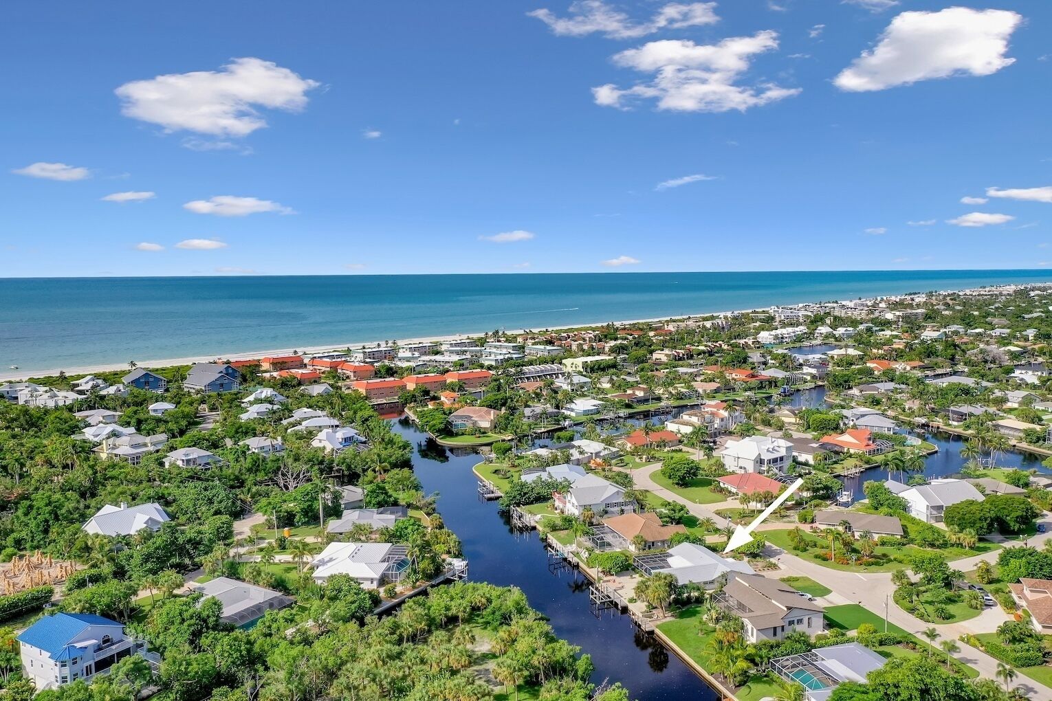 A coastal residential area with houses, a canal, and a beach.