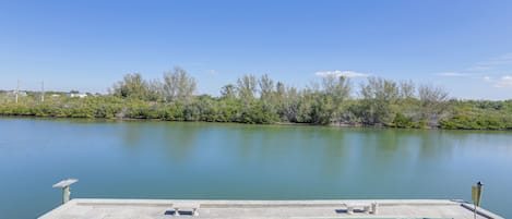 A serene lakeside view with a shuffleboard court and a small dock.