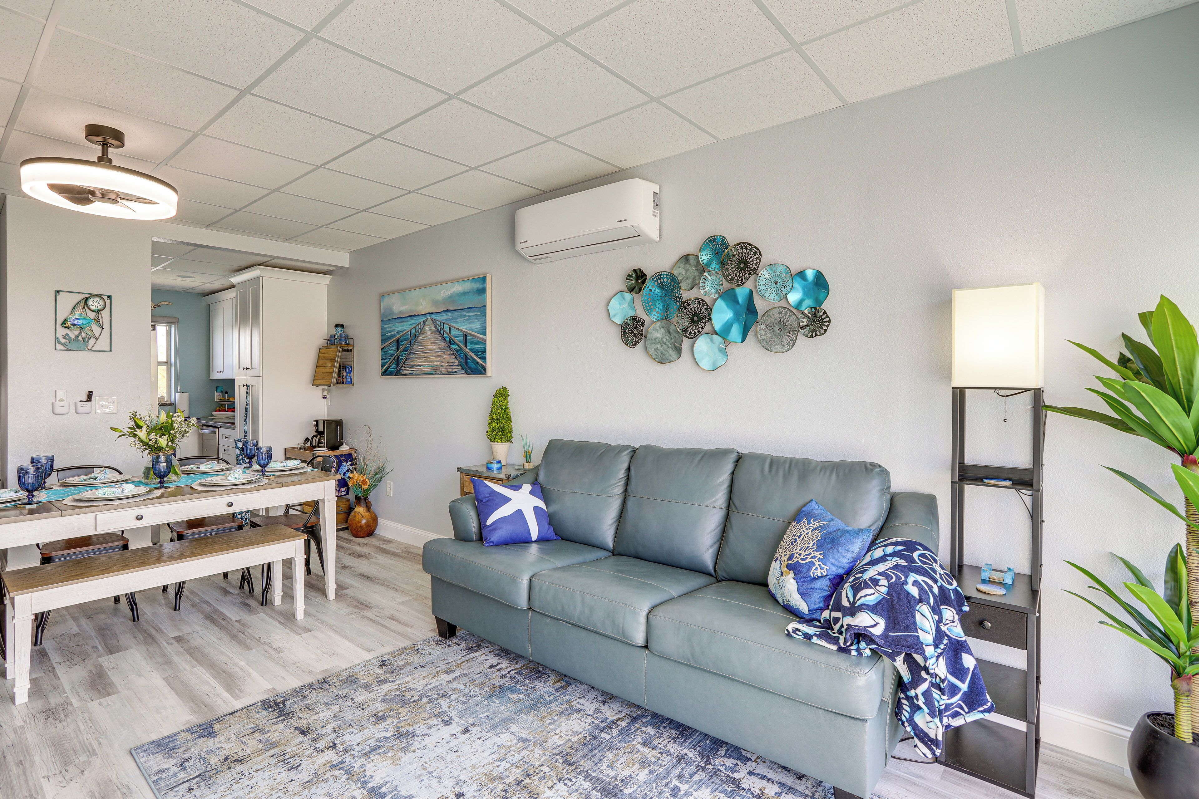 Un salon moderne avec un canapé gris, une table à manger décorée de bleu et de blanc, et un tapis à motifs.