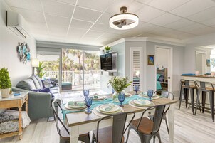 Zona pranzo moderna con tavolo in legno apparecchiato per quattro persone, bicchieri di vetro blu e una ventola a soffitto.