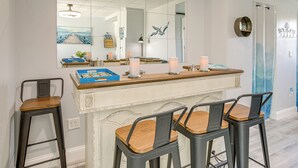 A bar area with a wooden counter, bar stools, and a large mirror reflecting the room. - Walk to Beach: Waterfront Indian Shores Condo (Indian Shores)