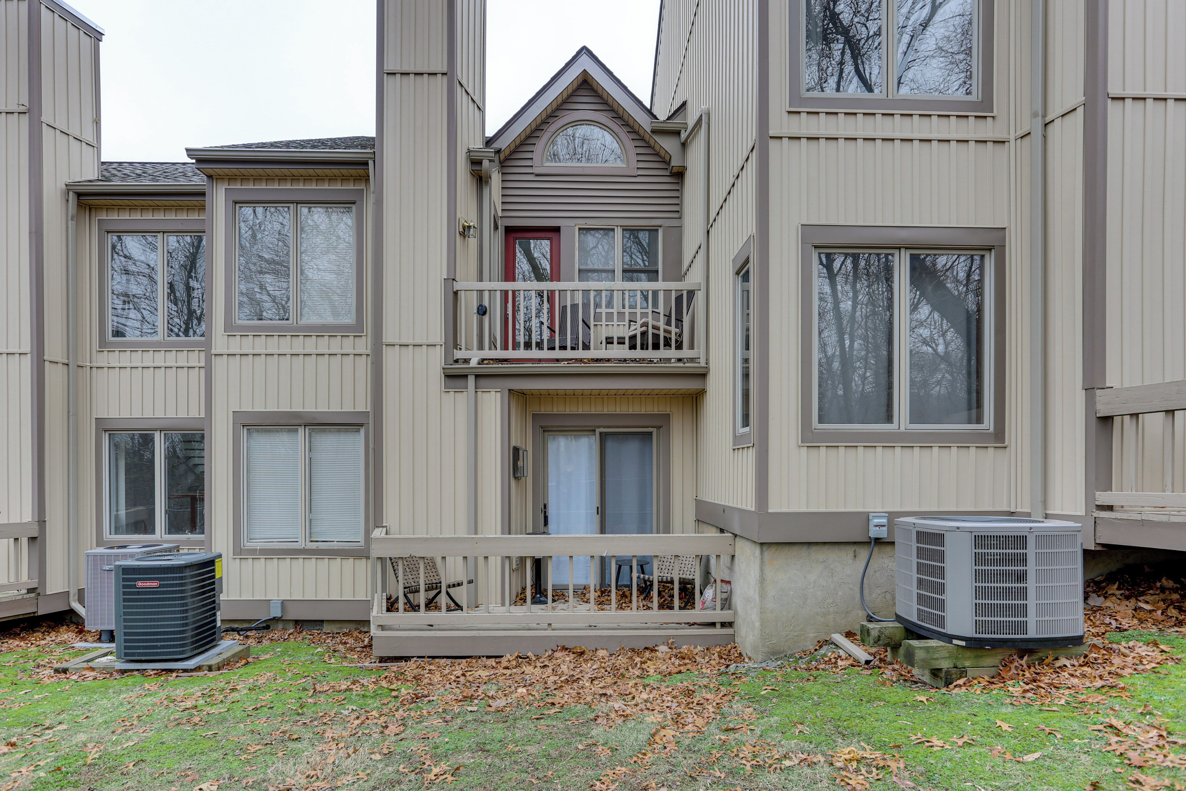 A multi-story residential building with a balcony, large windows, and an air conditioning unit.
