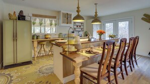 A kitchen with a central island, wooden chairs, pendant lights, and a refrigerator. - Vintage Coloma Home w/ Deck: Shop, Swim & Dine! (Coloma)