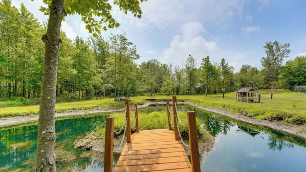 A wooden bridge over a calm pond, surrounded by lush greenery and trees. - Quiet Country Studio Between Saugatuck & Holland! (Holland)