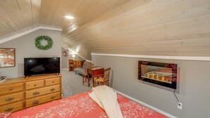 A bedroom with a bed, dresser, TV, fireplace, and a wooden ceiling. - Quiet Country Studio Between Saugatuck & Holland! (Holland)