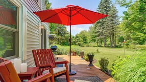A wooden deck with a red umbrella, a wooden chair, and a table with candles. - Quiet Country Studio Between Saugatuck & Holland! (Holland)