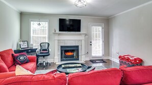 A living room with a fireplace, a television, and red furniture. - Comfy Augusta Condo w/ Deck ~ 4 Mi to Olde Town (Augusta)
