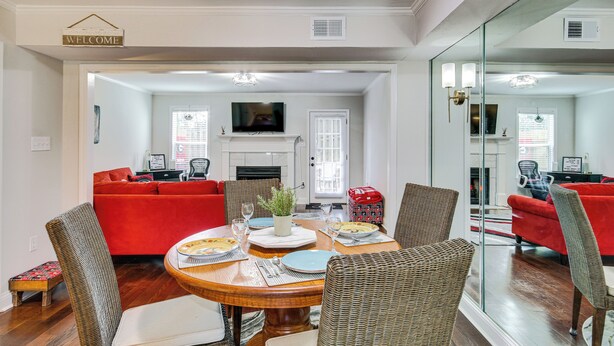 A dining area with a round table, wicker chairs, and a red sofa in the background. - Comfy Augusta Condo w/ Deck ~ 4 Mi to Olde Town (Augusta)