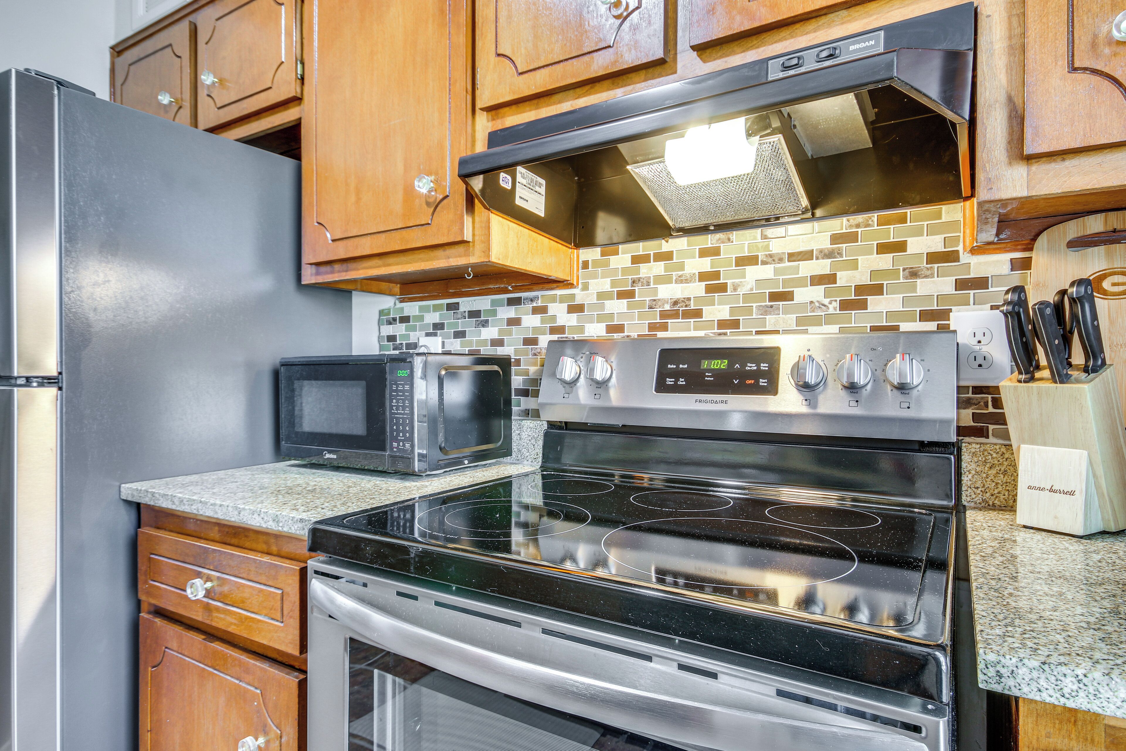 A kitchen with stainless steel appliances, wooden cabinets, and a tiled backsplash.