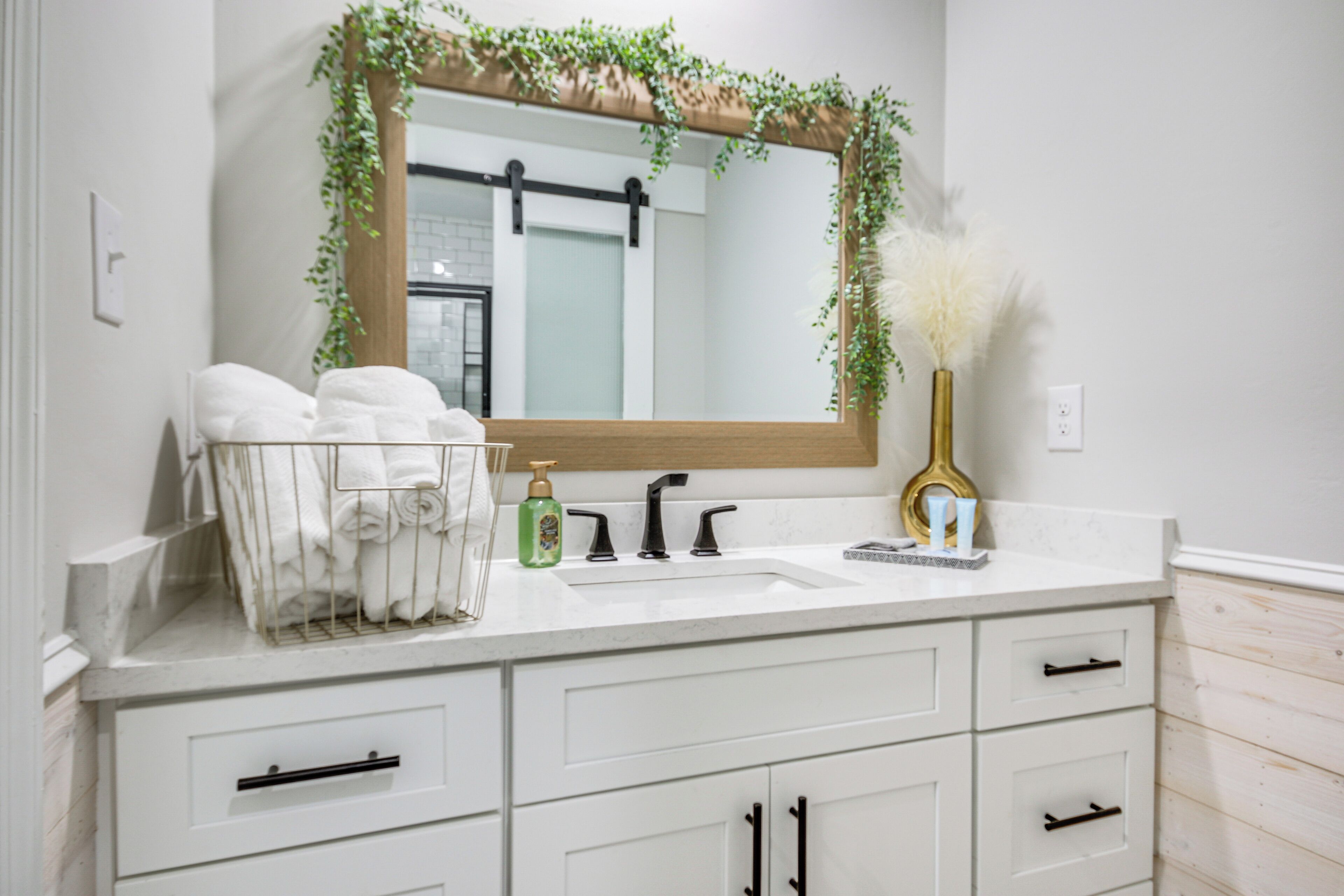 A bathroom with a white sink, a mirror with a wooden frame, and a towel rack with towels.