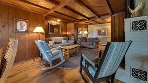 A cozy log cabin interior with wooden floors, a fireplace, two sofas, rocking chairs, and framed artwork on the walls. - Cozy Harbor Springs Vacation Rental, 13 Mi to Town (Harbor Springs)