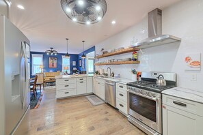 A modern kitchen with white cabinetry, a stainless steel stove, and wooden flooring.