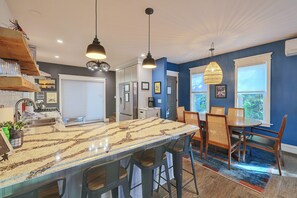 A modern kitchen with a large island, bar stools, pendant lighting, and a dining area with a table and chairs. - 17 Mi to Ski Slopes! Retreat Near Lake Michigan (Frankfort)