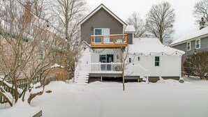Ein zweistöckiges Haus mit einer Holzterrasse und einer überdachten Veranda.