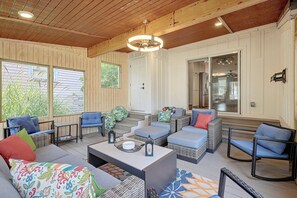 A spacious living area with a high ceiling, built-in wooden walls, and a large window overlooking greenery.