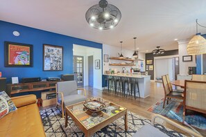 A modern living room with a sofa, coffee table, and a dining area with chairs. - 17 Mi to Ski Slopes! Retreat Near Lake Michigan (Frankfort)