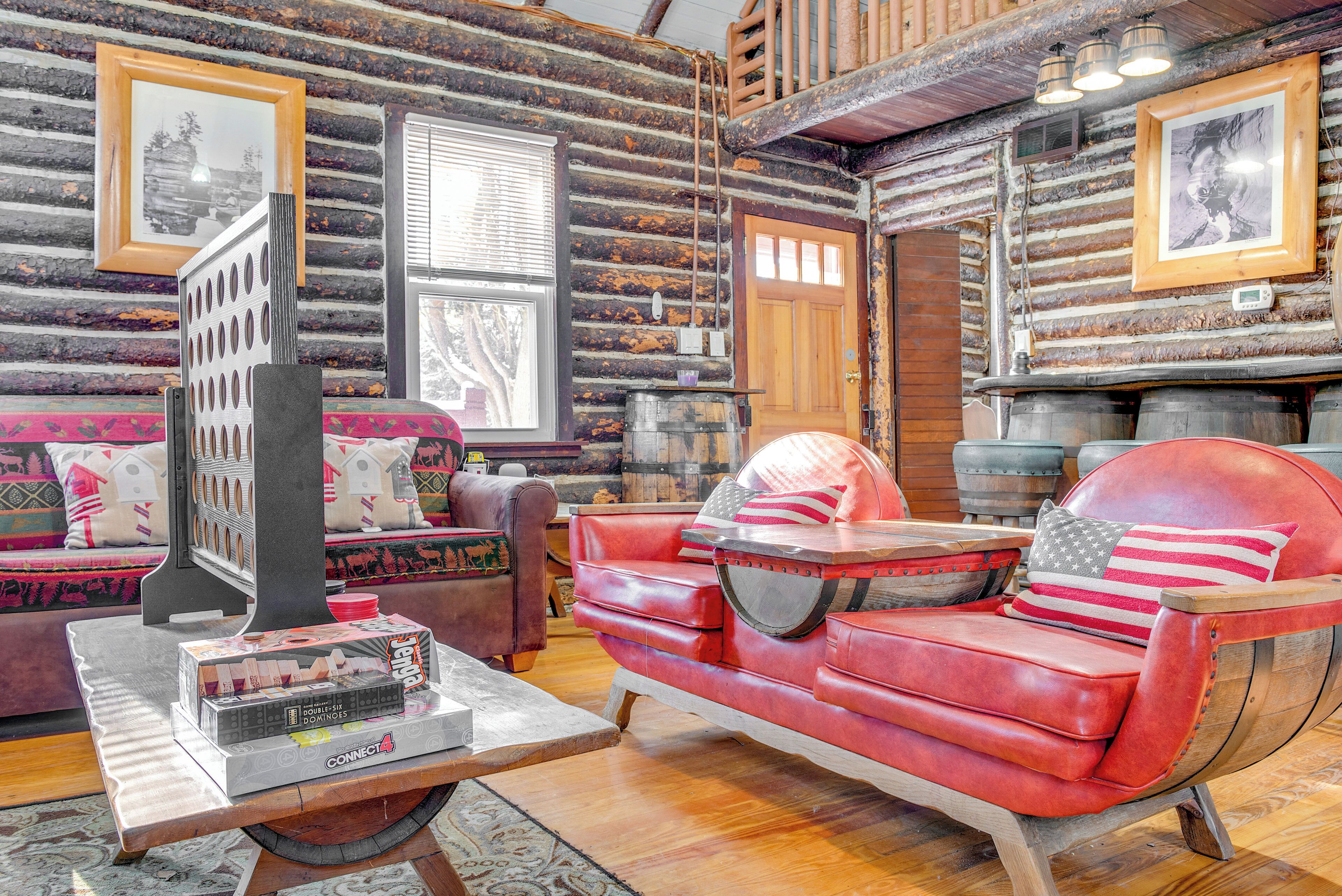 Interior de uma cabana de madeira com um sofá de couro vermelho, uma mesa de centro de madeira e um quadro na parede.