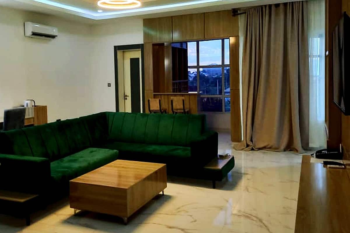 A modern living room with a sectional sofa, a wooden coffee table, and a flat-screen TV mounted on the wall.