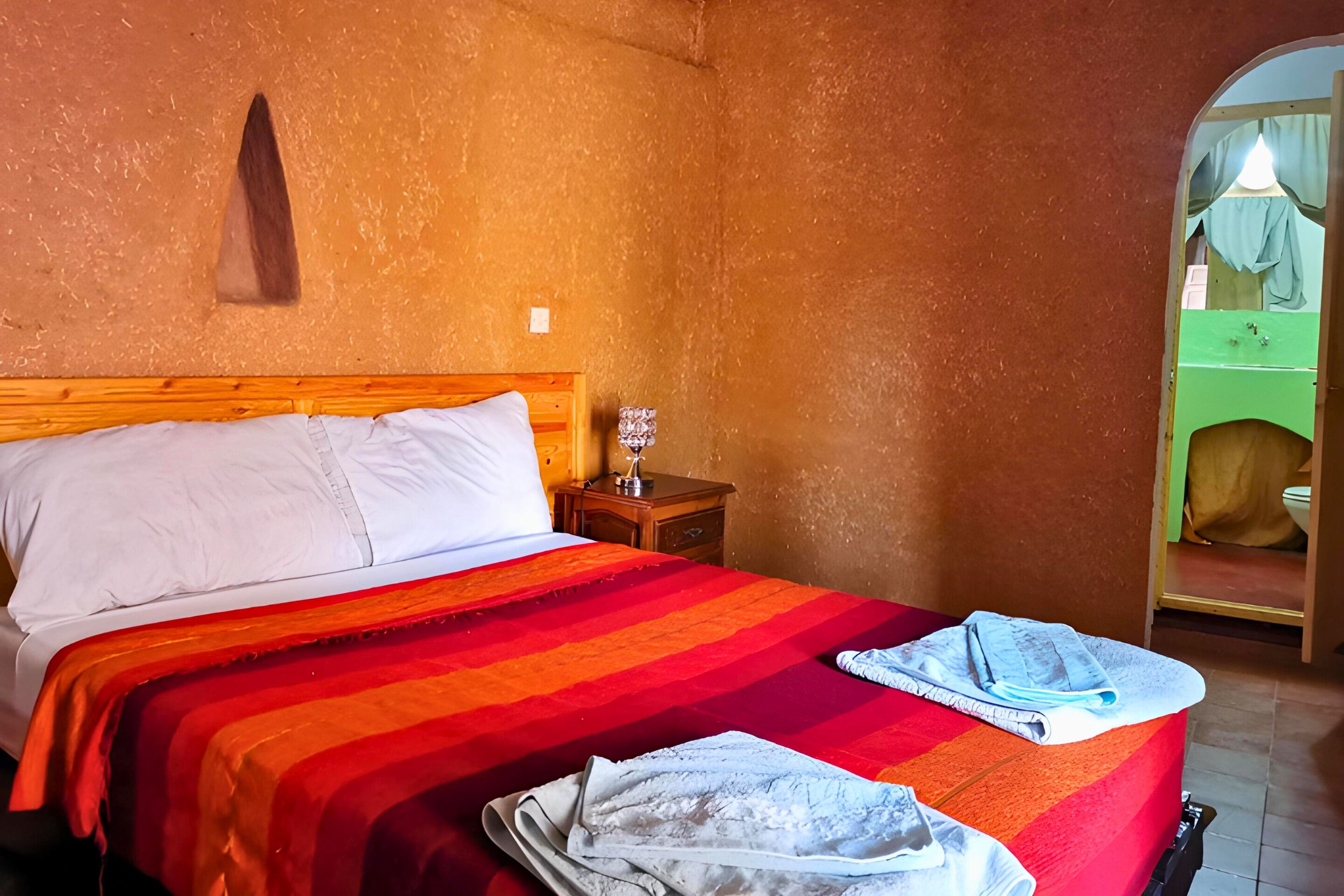 A room with a bed, a nightstand, and a mirror.