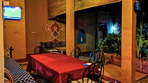 Comedor con mantel rojo, sillas estampadas y una pantalla de televisión mostrando un evento deportivo.