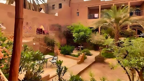 Un patio con una palmera, una mesa con sillas y un edificio con balcones.