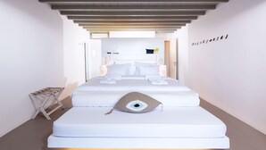 Ein modernes Hotelzimmer mit einem großen Bett, einem kleinen Nachttisch und Blick auf den Flur.