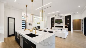A modern kitchen with a marble island, black cabinets, and gold fixtures.