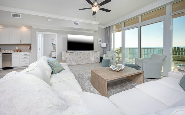 A modern living room with a white sofa set, a wooden coffee table, and a flat-screen TV. - Phoenix Gulf Towers 1605 4 Bedroom Condo (Orange Beach)