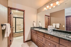 Un baño con tocador de madera, un espejo grande y zona de ducha.