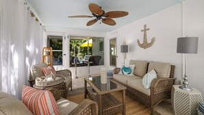 A cozy living room with wicker furniture, a ceiling fan, and nautical decor. - Mermaid's Treasure 2 Bedroom Home by RedAwning (Anna Maria)