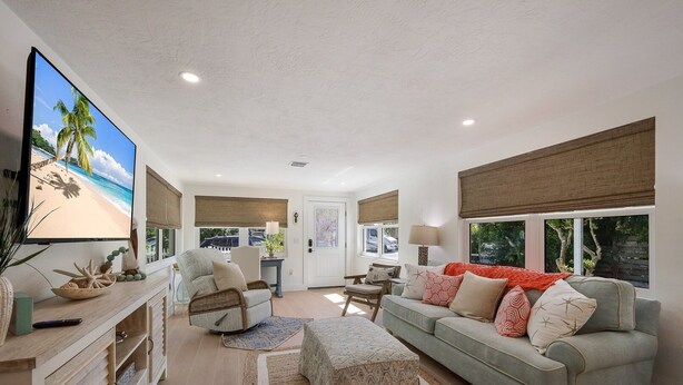 A spacious living room with a large flat-screen TV, comfortable seating, and a view of the outdoors. - Mermaid's Treasure 2 Bedroom Home by RedAwning (Anna Maria)