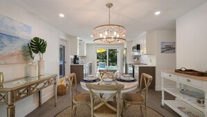 A spacious dining area with a round table, wooden chairs, and a chandelier. - Mermaid's Treasure 2 Bedroom Home by RedAwning (Anna Maria)
