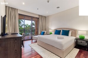 Ein modernes Hotelzimmer mit einem großen Bett, einem Schreibtisch, einem Stuhl und einem Balkon mit Blick auf Palmen.
