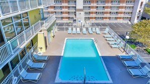 Ein Pool auf dem Dach mit blauen Liegestühlen und freiem Blick auf die umliegenden Gebäude.