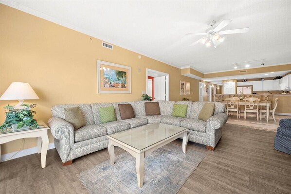 A living room with a sofa, coffee table, and a dining area with chairs and a table.