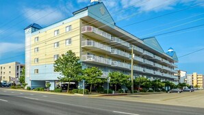 Ein mehrstöckiges Hotel mit Balkonen, einem sichtbaren Sandwichgeschäft und wolkenlosem Himmel.