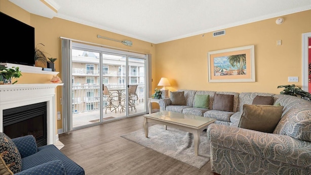Ein Wohnzimmer mit Kamin, einer Couch, einem Couchtisch und einem Balkon mit Gartenmöbeln.