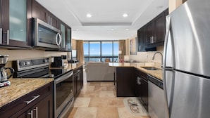 A modern kitchen with stainless steel appliances, dark cabinetry, and a large window offering a view of the ocean. - Century One-2 Bedroom Ocean Oasis with Indoor Pool! (Ocean City)