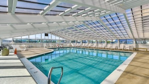 An indoor swimming pool with a glass ceiling, sun loungers, and a view of the sky. - Century One-2 Bedroom Ocean Oasis with Indoor Pool! (Ocean City)