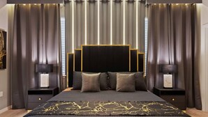 Une chambre à coucher moderne avec un grand lit, deux tables de chevet et une tête de lit dotée d’un éclairage intégré.