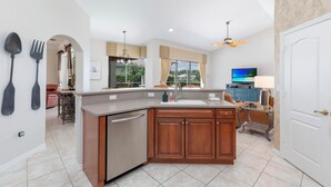 A modern kitchen with a built-in dishwasher, wooden cabinets, and a large island. - Stunning Briarwood Lakefront Pool and Spa Home (Naples)