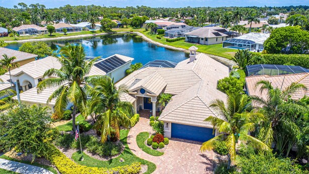 A residential area with houses, a swimming pool, and lush greenery. - Stunning Briarwood Lakefront Pool and Spa Home (Naples)