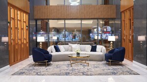 Un hall moderno con un sofá grande, dos sillones, una mesa de centro y una alfombra estampada.